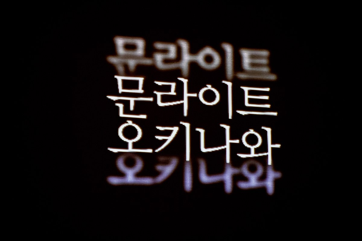 <문라이트 오키나와>의 한 장면. 검은 배경에 ‘문라이트 오키나와’라는 흰 글자가 떠 있고, 글자 위아래로 같은 문구가 흐릿하게 겹쳐 보인다.
