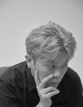 김재훈 연출가의 프로필 사진. 흑백 사진으로, 밝은 색으로 염색한 짧은 머리에 검은 셔츠를 입은 사람이 한 손으로 얼굴을 짚은 채 옆쪽 아래를 바라보고 있다.