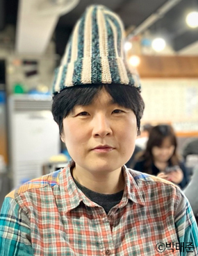 작가이자 연출가인 김풍년의 프로필 사진. 짧은 검은 머리에 줄무늬 모자를 쓰고, 체크무늬 셔츠를 입었다. 정면을 바라보며 살짝 미소를 짓고 있다.